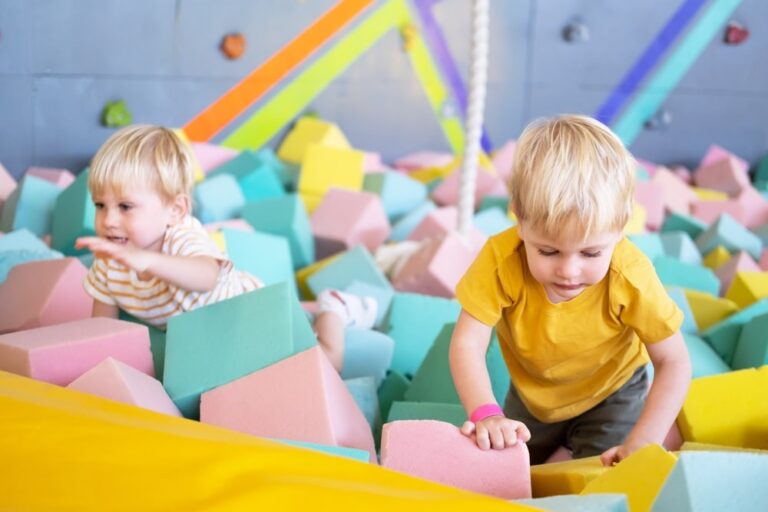 two cute little boys twins plays with soft cubes in the dry pool in play center